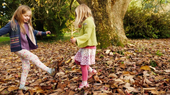 Plant yn mwynhau dail yr hydref yng Ngerddi Dyffryn, Cymru